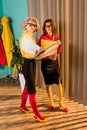 beautiful retro styled businesswomen in colorful blouses looking at documents in folder