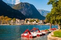 Beautiful Riva del Garda cityscape with vibrant red pedal boats parked in a row on the beach and city surrounded by high dolomite Royalty Free Stock Photo