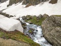 Beautiful river stream flowing in between a huge rock on one side and a snow glacier on other side in an epic Indian Himalayan Val Royalty Free Stock Photo