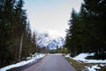 A beautiful road among a dense forest. View of the mountains, mountains in the snow and fog Royalty Free Stock Photo