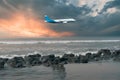 Beautiful rocks on the sea shore, big waves, airplanes flying in the sky. The sun is going down.