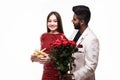 Beautiful romantic asian couple, young asian woman in dress holding red roses and handsome indian man in suit are in love isolated Royalty Free Stock Photo