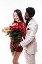 Beautiful romantic asian couple, young asian woman in dress holding red roses and handsome indian man in suit are in love isolated Royalty Free Stock Photo