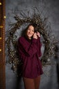 Beautiful romantic brunette woman in pajamas in cozy loft style room with garlands and rustic wreath. Portrait authentic