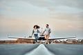 Beautiful romantic couple is holding hands, looking at each other and smiling while running on take-off ground near the aircraft Royalty Free Stock Photo