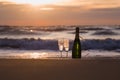 Bottle of champagne with two glasses on the beach against the backdrop of sunset. Romantic evening, lovers, New Year, wedding or Royalty Free Stock Photo