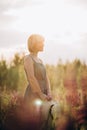 Beautiful romantic girl blonde in a dress in a field of purple flowers of lupins at dawn holds a hat in his hands Royalty Free Stock Photo