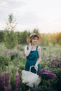 Beautiful romantic girl blonde in a dress and hat in a field with a bouquet of purple flowers of lupins at dawn Royalty Free Stock Photo