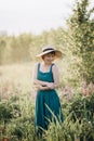Beautiful romantic girl blonde in a dress and hat in a field of purple flowers of lupins at dawn Royalty Free Stock Photo