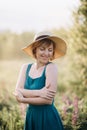 Beautiful romantic girl blonde in a dress and hat in a field of purple flowers of lupins at dawn Royalty Free Stock Photo