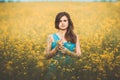 Beautiful romantic girl on blooming rapeseed field enjoying nature, young elegant woman walks Royalty Free Stock Photo