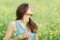 Beautiful romantic girl on blooming rapeseed field enjoying nature, young elegant woman walks Royalty Free Stock Photo
