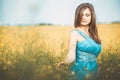 Beautiful romantic girl on blooming rapeseed field enjoying nature, young elegant woman walks Royalty Free Stock Photo