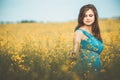 Beautiful romantic girl on blooming rapeseed field enjoying nature, young elegant woman walks Royalty Free Stock Photo