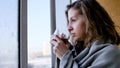 Beautiful romantic girl with a cup of tea near the winter window. Winter day, cozy mood. Royalty Free Stock Photo