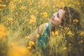 Beautiful romantic girl sitting on blooming rapeseed field enjoying nature, young elegant woman walking, pretty female face Royalty Free Stock Photo