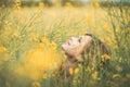 Beautiful romantic girl sitting on blooming rapeseed field enjoying nature, young elegant woman walking, pretty female face Royalty Free Stock Photo