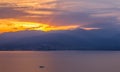 Beautiful romantic landscape dramatic sunset behind mountains silhouettes above calm sea bay with small boat and sun glare Royalty Free Stock Photo