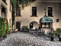 Old iron well on a historic castle background where there are trees amd flowers Royalty Free Stock Photo