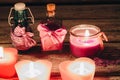 Beautiful romantic pink candles with aroma bottles on wooden background.