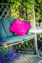 Beautiful, romantic seat in the garden with pink cushion and climbing ivy.