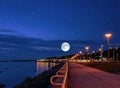 Beautiful romantic starry night and full moon on blue sky at sea , city promenade and city lights blurred at water lifestyle in Ta