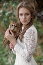 Beautiful romantic woman with an owl. The bird sits on her hand.