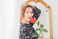 Beautiful romantic young blonde woman in dress with red rose near mirror Royalty Free Stock Photo