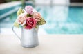 Beautiful rose paper flower in metal pot over blurred swimming pool background Royalty Free Stock Photo