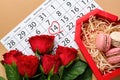 Beautiful roses, calendar and box with macaroons on table. Valentines Day celebration