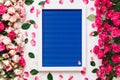 Beautiful roses directed at each other and empty wooden frame on blue texture