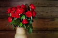 Beautiful roses with frech and wilted buds in ceramic jug on rustic wooden background