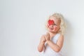 Beautiful rouge smiling happy female child covers face with heart stick, has pleasant smile, isolated over white