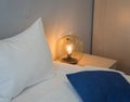 A beautiful round lamp shines near bedside table Royalty Free Stock Photo