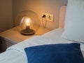A beautiful round lamp shines near bedside table Royalty Free Stock Photo