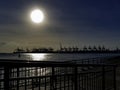 Beautiful round sun by the seaside with seaport in the background