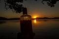 beautiful rum bottle full with rum holding in front of a sunset over Watson Taylors Lake at Crowdy Bay National Park, New South Royalty Free Stock Photo