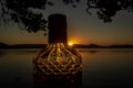 beautiful rum bottle full with rum holding in front of a sunset over Watson Taylors Lake at Crowdy Bay National Park, New South Royalty Free Stock Photo