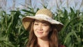 A beautiful rural girl under shade of an elegant straw hat in the green field of corn. Photo of a happy country female Royalty Free Stock Photo