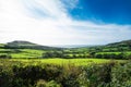 Beautiful rural landscape with blue sky, green hills and meadows, and sea on the horizon. Autumn or winter sunny day Royalty Free Stock Photo