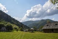 Old wooden houses on a green meadow in mountains. Ukrainian Carpathian village Royalty Free Stock Photo