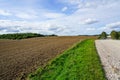 Beautiful rural landscape with plowed field, gravel road, forest and blue sky Royalty Free Stock Photo