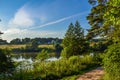 Beautiful rural landscape. Residential house near the river. Trees with bright greenery and blue sky with beautiful clouds. Summer