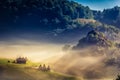 Beautiful rural mountain landscape in the morning light with fog, old houses and haystacks Royalty Free Stock Photo