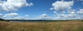 Beautiful rural panoramic landscape with lake after meadow and white clouds on blue sky on sunny summer day Royalty Free Stock Photo