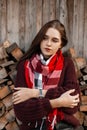 Beautiful rural young woman in stylish knitted warm clothes in a vintage scarf posing near an old wooden barn outdoors outside the Royalty Free Stock Photo