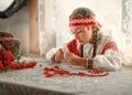 A beautiful Russian girl diligently collects Rowan berries on a thread