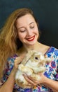 Beautiful russian woman with long blond hair holding a rabbit pet in her hands against black wall Royalty Free Stock Photo