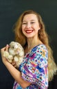 Beautiful russian woman with long blond hair holding a rabbit pet in her hands against black wall Royalty Free Stock Photo