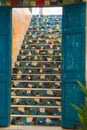 A beautiful rustic blue wooden set of doors, leading up to a lovely tiled stairway, in a very creative seaside restaurant.